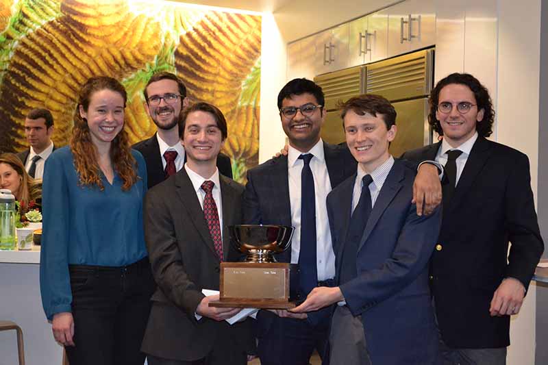 six students hold a trophy for winning a capstone project.